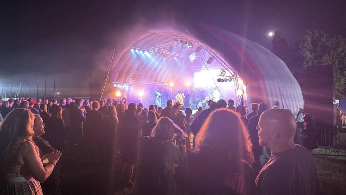 Crowd in front of a lit festival stage at night
