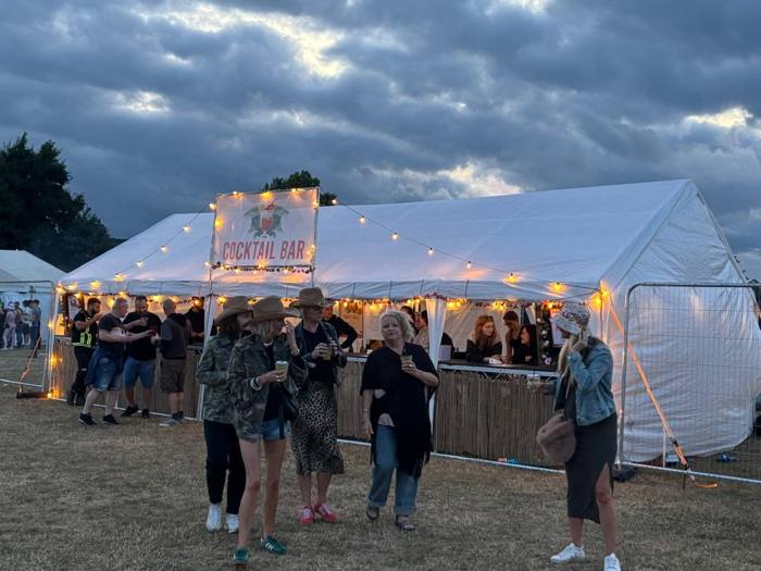 Cocktail bar marquee with festival-goers at dusk
